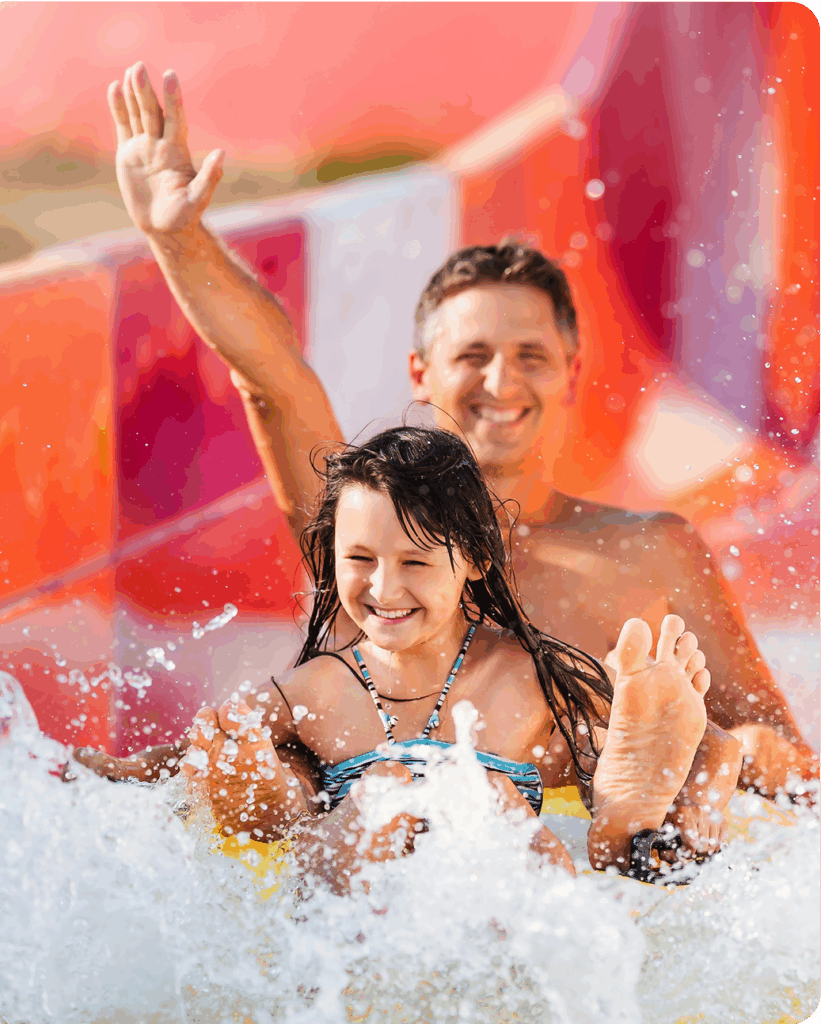 Man and child smiling going down a water slide.