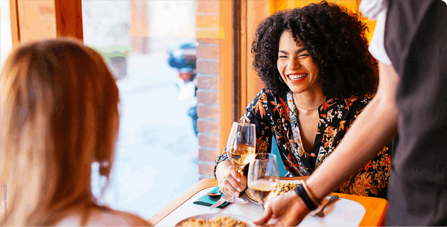 Two women at a table smiling drinking wine