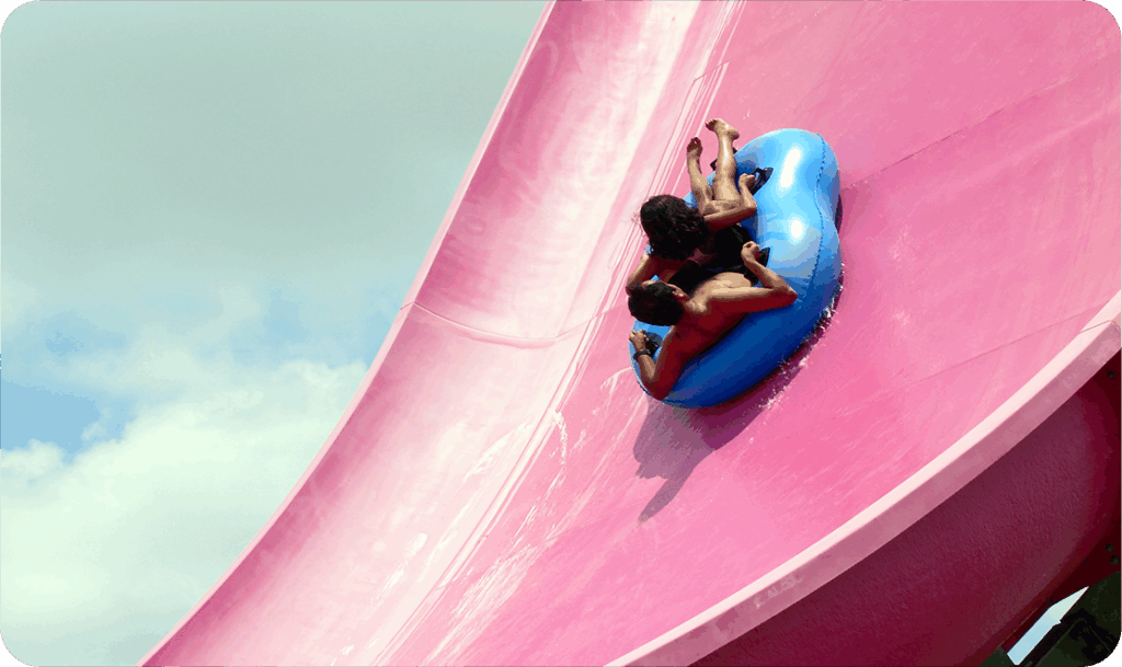 Man and child going down a waterslide in a tube.