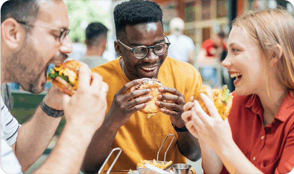 Group of friends eating burgers at a table outside