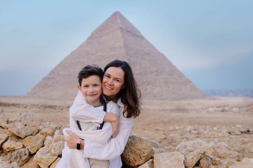 Mother holding child in front of the pyramids.