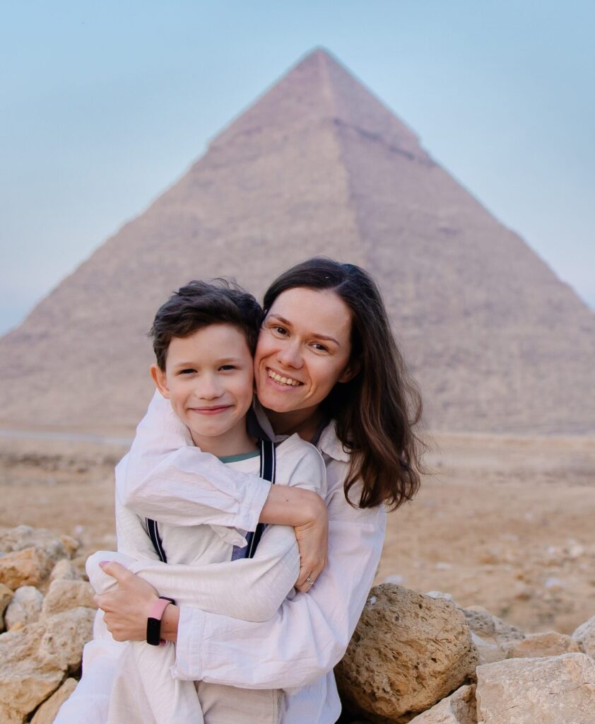 Mother holding child in front of the pyramids.