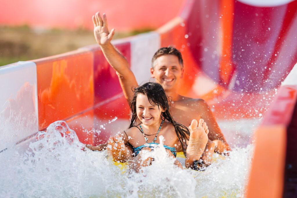 Father and daughter smiling going down a waterslide