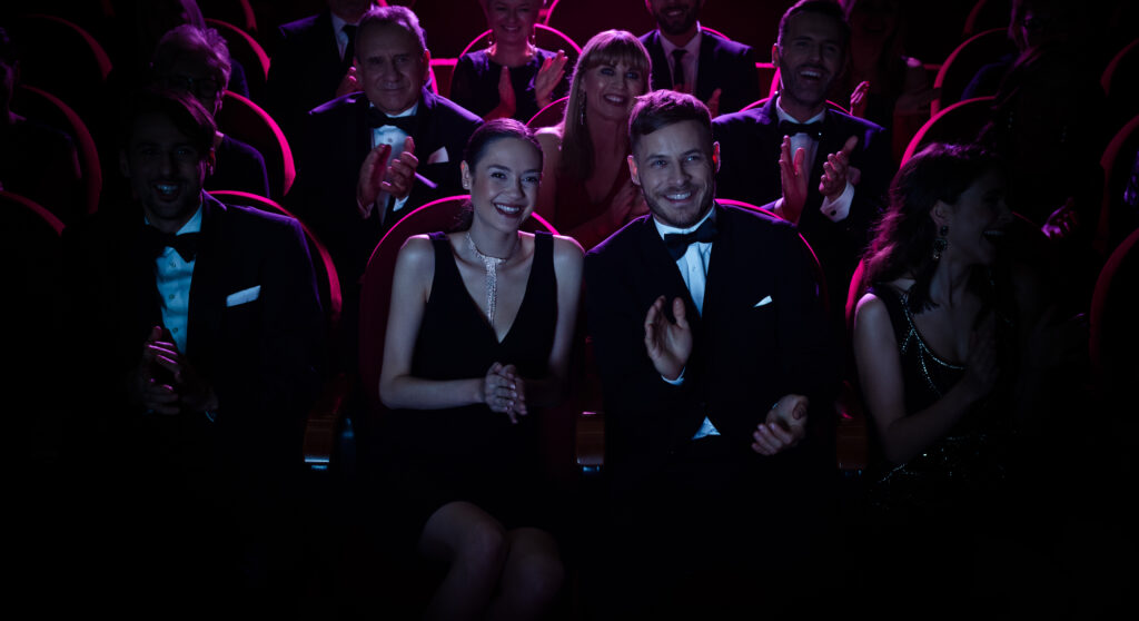 Smiling crowd applauding while watching opera