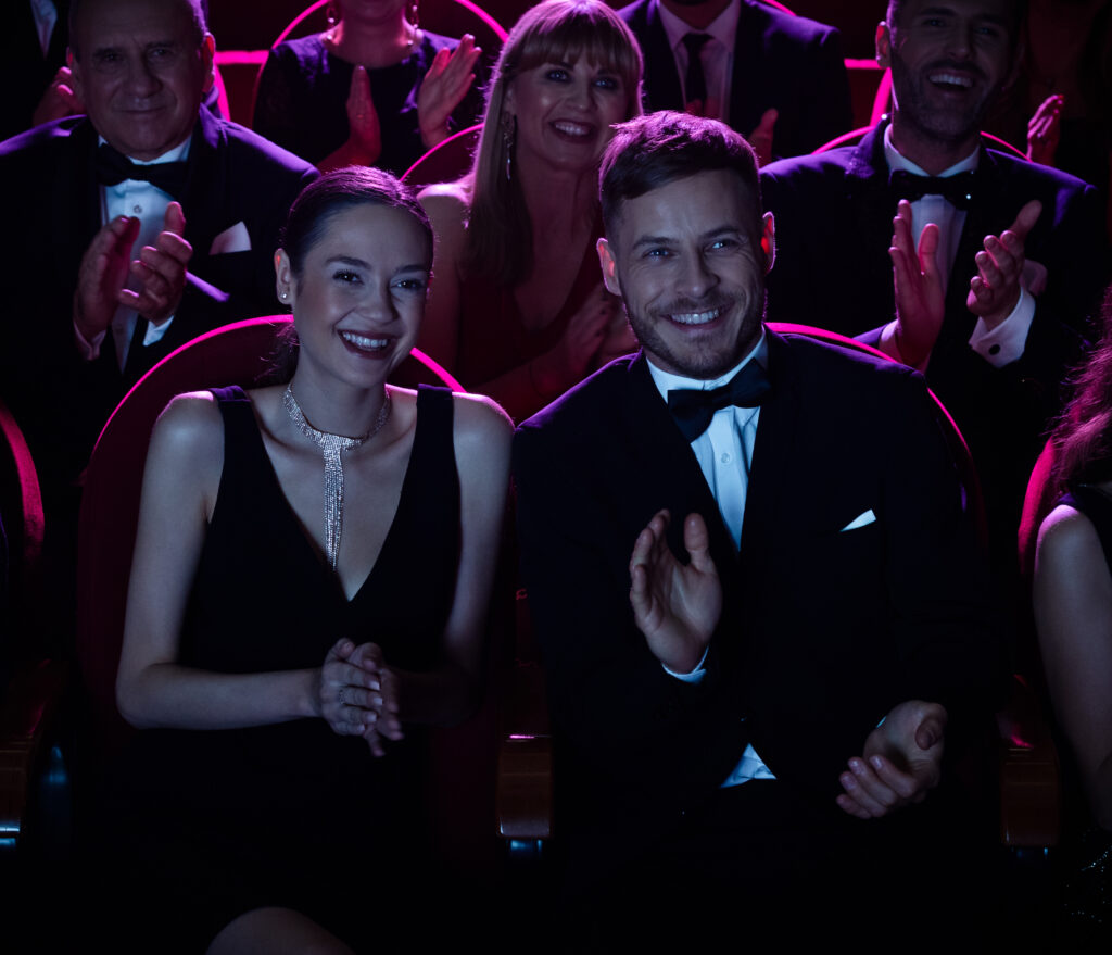 Smiling crowd applauding while watching opera