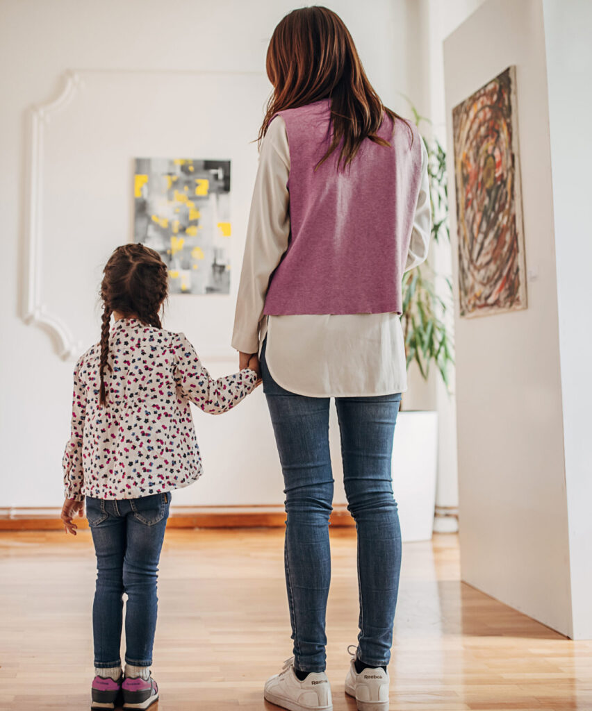 Diverse group of visitors in modern art gallery. Mother brought her little daughter.
