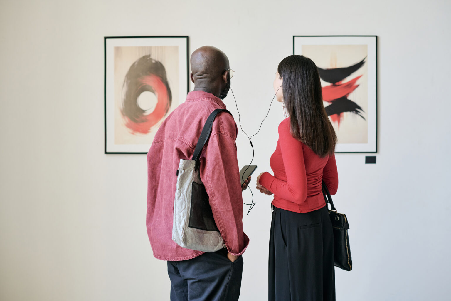People Attending an Art Gallery Exhibition Displaying Paintings