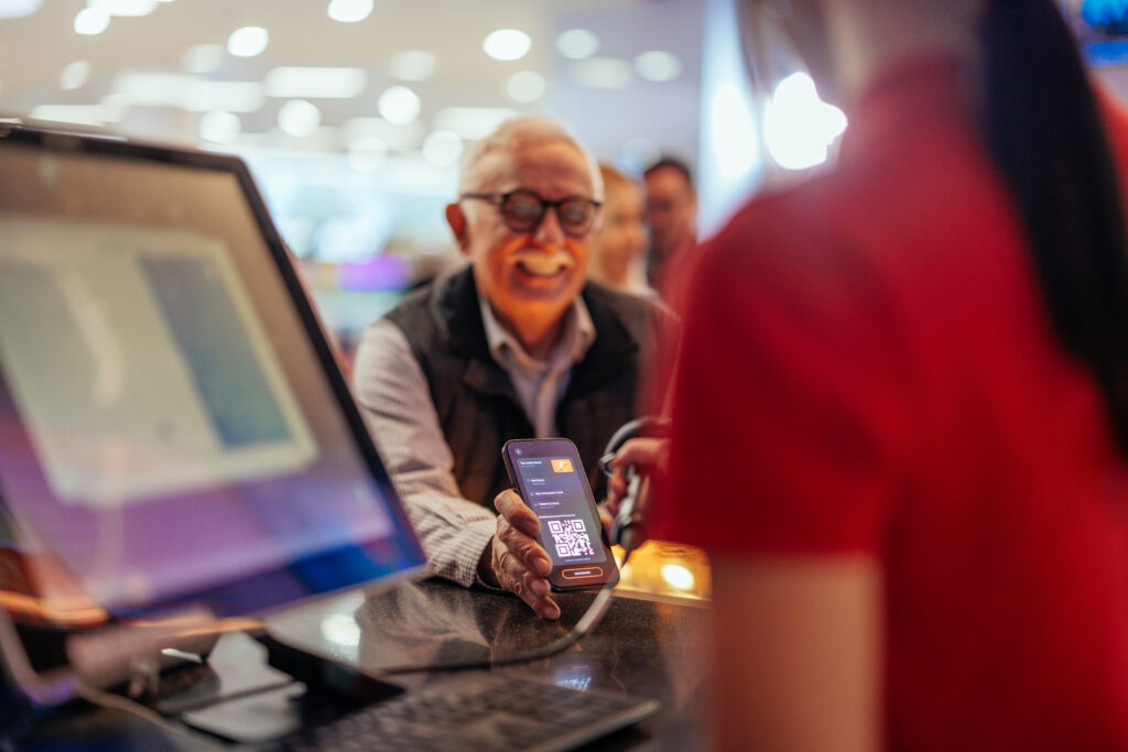Senior man paying with mobile app in cinema.