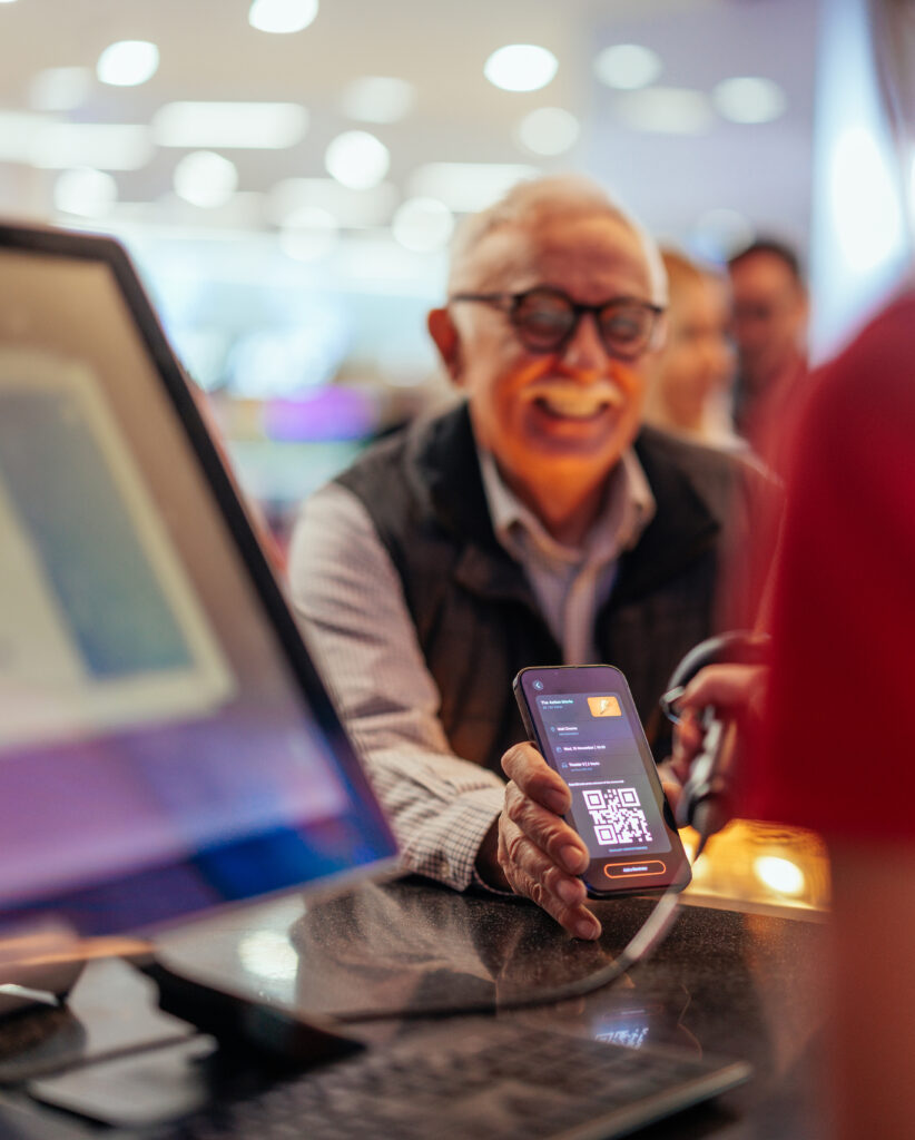 Senior man paying with mobile app in cinema.