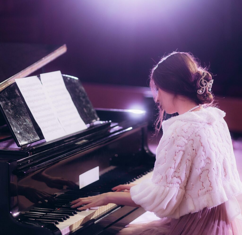 Close up view of a girl plays piano in the concert hall at scene