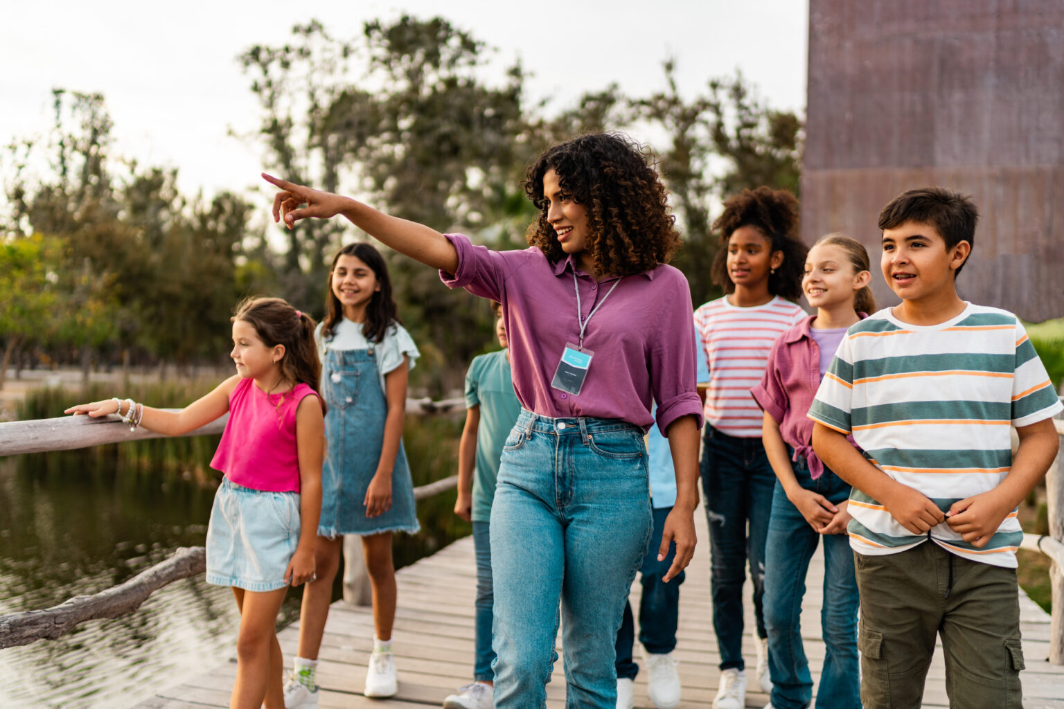 Young teacher walking and talking to students during field trip on zoo