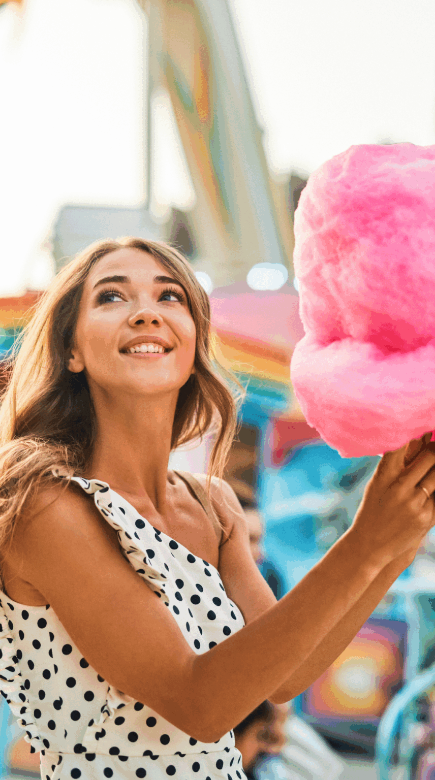 Woman holding cotton candy at a theme park.