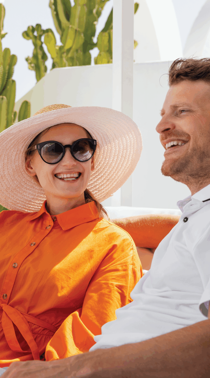 Woman wearing hat smiling outside next to man at resort.